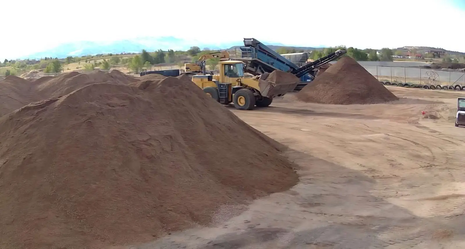 Two wheel loaders feeding a Kleemann crusher unit with mountains in the background